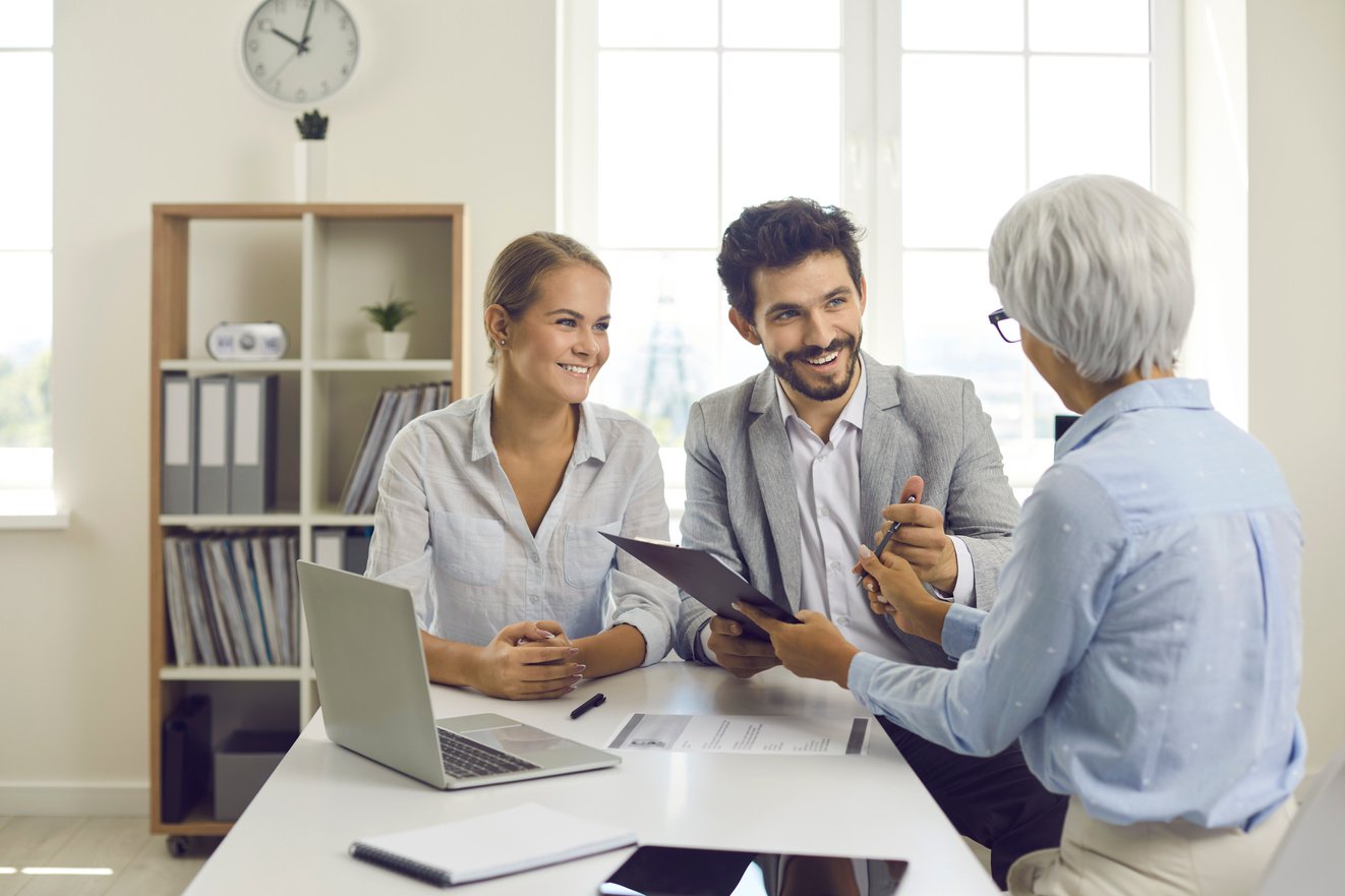 Happy Couple Signing Contract during Meeting with Banking Agent, Realtor or Mortgage Broker